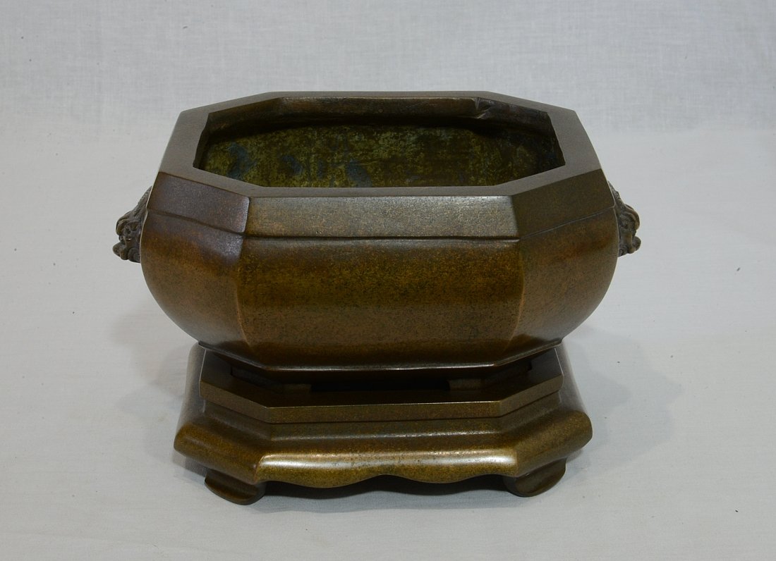 Chinese Octagon Bronze Incense Burner With Mark: Chinese octagon bronze incense burner on bronze stand, decorated with lion heads on the side. Four character relief studio mark on the bottom. Good condition. 7.5" wide x 4" height.