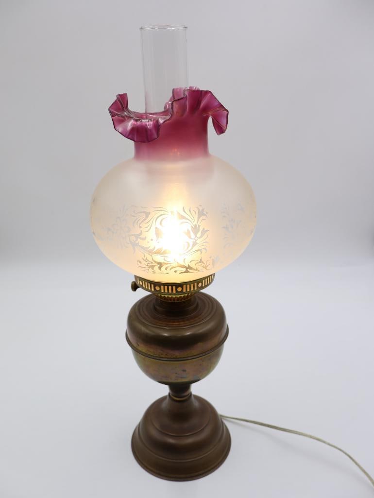 Victorian Style Electric Oil Lamp: Features a frosted glass shade with ornate design and ruffle cranberry accent at top. Bottom is brass oil lamp that has been converted for electricity.