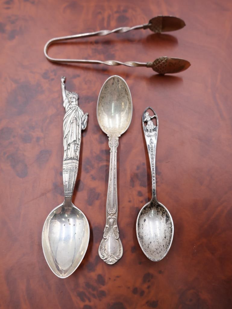 Collection of Antique Sterling Souvenir spoons and Acorn Tongs: The prominent spoon on the left features a detailed Statue of Liberty finial, Sterling Silver acorn designed tongs. Please view photos for weight. 