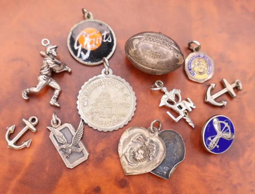 Collection of vintage sterling silver bracelet charms: The collection includes assorted designs such as a baseball player, a football, anchors, a Washington D.C. monument, and a New York Giants logo. 