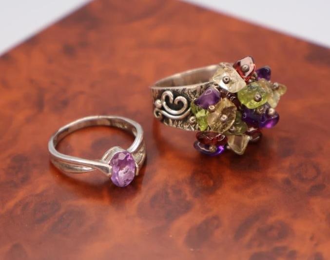 These are sterling silver rings with semi-precious stones: The rings shown are most likely sterling silver rings with semi-precious stones, specifically an amethyst solitaire ring and a multi-gemstone cluster ring, 