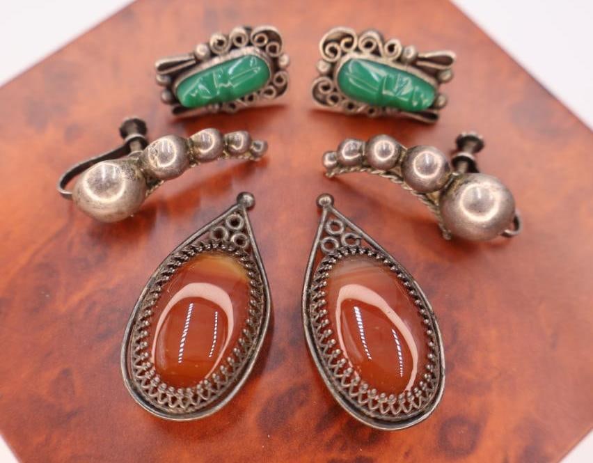 Collection of vintage sterling silver and gemstone earrings: Stones include orange carnelian the teardrops, featuring a pair with carved green onyx or jadeite earrings. Click on the main photo to view more photos of this lot. Weight and length can be viewed in