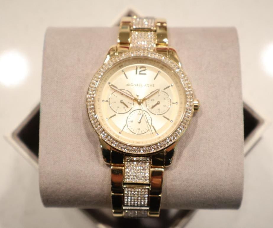 Michael Kors Tibby Watch: Featuring an oversized 40mm-44mm polished gold-tone stainless steel design with a matching gold dial. It stands out with a pave crystal-set topring and center links on the bracelet. Key features inclu