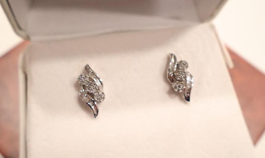 Pair of 10K solid white gold designer diamond cluster stud earrings: The center of each earring is composed of a cluster of small round-cut diamonds, flanked by polished white gold curves that create a dynamic, flowing silhouette. Original tag marked $299, '1/3 cttw
