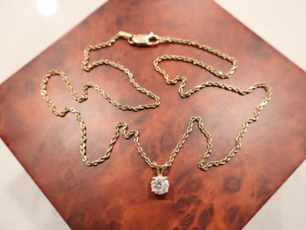 Classic 14K yellow gold diamond solitaire pendant necklace: A round brilliant-cut diamond solitaire. Based on its visual scale against the chain, the diamond appears to be in the 0.25 to 0.50 carat range. It is securely held in a traditional 4-prong basket