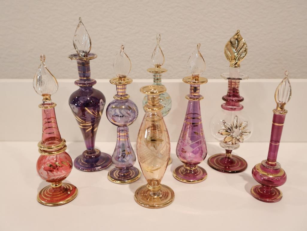 Exquisite collection of seven authentic hand-blown Egyptian glass perfume bottles: These delicate vessels are renowned for their vibrant colors and 14kt gold-painted accents, often referred to as "Pyrex" glass for their thin yet durable quality. Each bottle is individually crafted