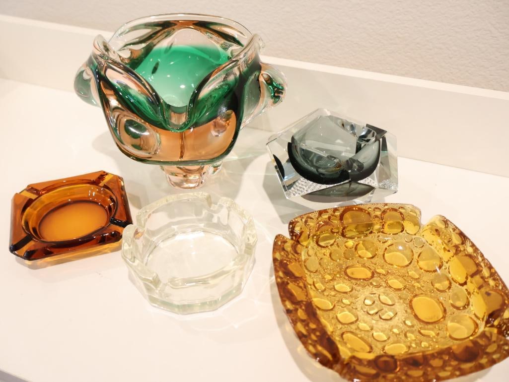 Collection of five mid-century art glass ashtrays and decorative bowls: Bohemian Art Glass Centerpiece, Geometric Murano Glass Ashtray, Vintage Amber Pebble Glass Ashtray and additional Decorative ashtrays. Showcasing iconic European craftsmanship from the 1960s and