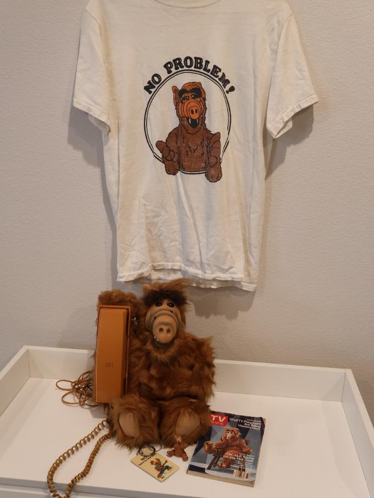 Nostalgic collection of vintage memorabilia centered on ALF: Vintage ALF No Problem T-Shirt. Accompanying the shirt is a large ALF stuffed animal, which was a widely popular toy during the show's original run. 