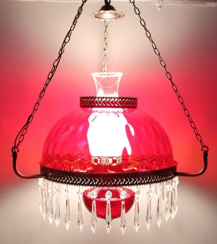 Antique Ruby Red Glass Parlor Lamp: This lovely red ruby glass parlor lamp features wavy red glass shade with brass housing, crystal drops and oil lamp chimney. This lamp has been retrofitted with an electric lamp and is a plug in so