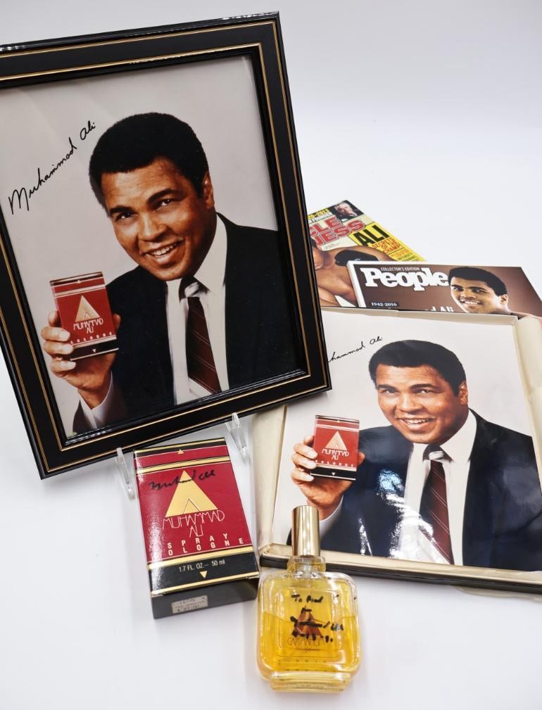 Muhammead Ali Signed Cologne and Memorabilia: Muhammad Ali signed box and cologne bottle, along with promotional framed headshots and magazines featuring the historic boxing legend