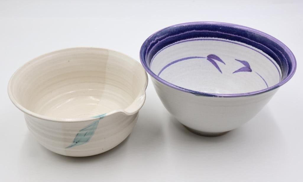 Two Stoneware Artisan Made Bowls: Light turned pottery bowl with pour spout and leaf like handle, and blue glaze bowl