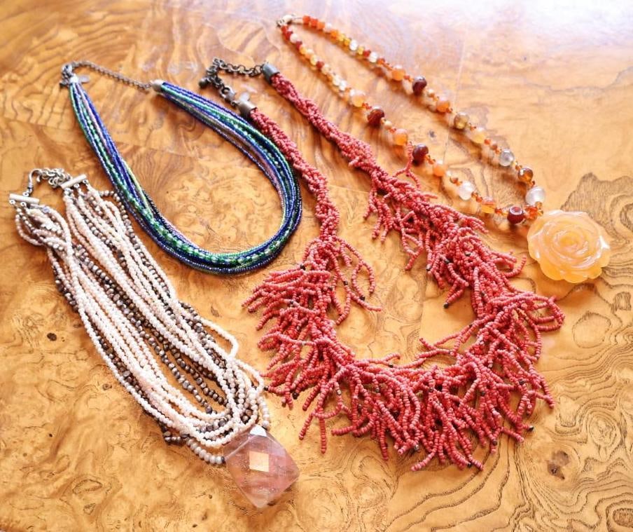 Artisan Multi-Strand Beaded and Stone Necklace Collection: Collection of four statement necklaces featuring coral-colored seed beads, multicolor glass beads, warm-toned stone beads with carved rose pendant, and multi-strand freshwater pearl style beads with