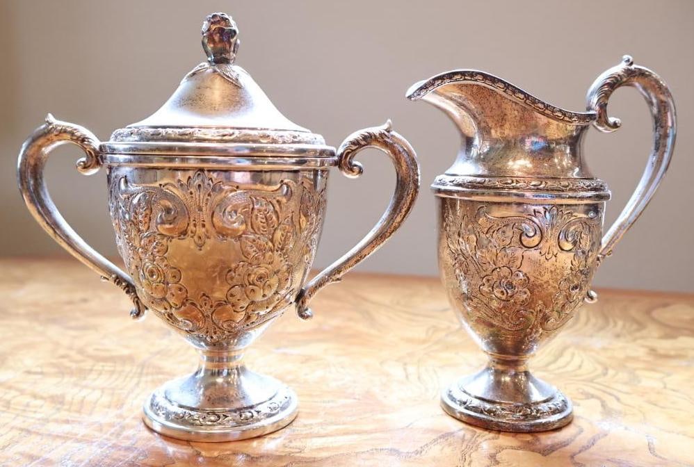 Frank M. Whiting and Co. Hand-Chased Sterling Silver Creamer & Covered Sugar Bowl: Matching Frank M. Whiting and Co. sterling silver creamer and covered sugar bowl featuring ornate hand-chased floral and scroll decoration. Both pieces are raised on pedestal bases with decorative bor