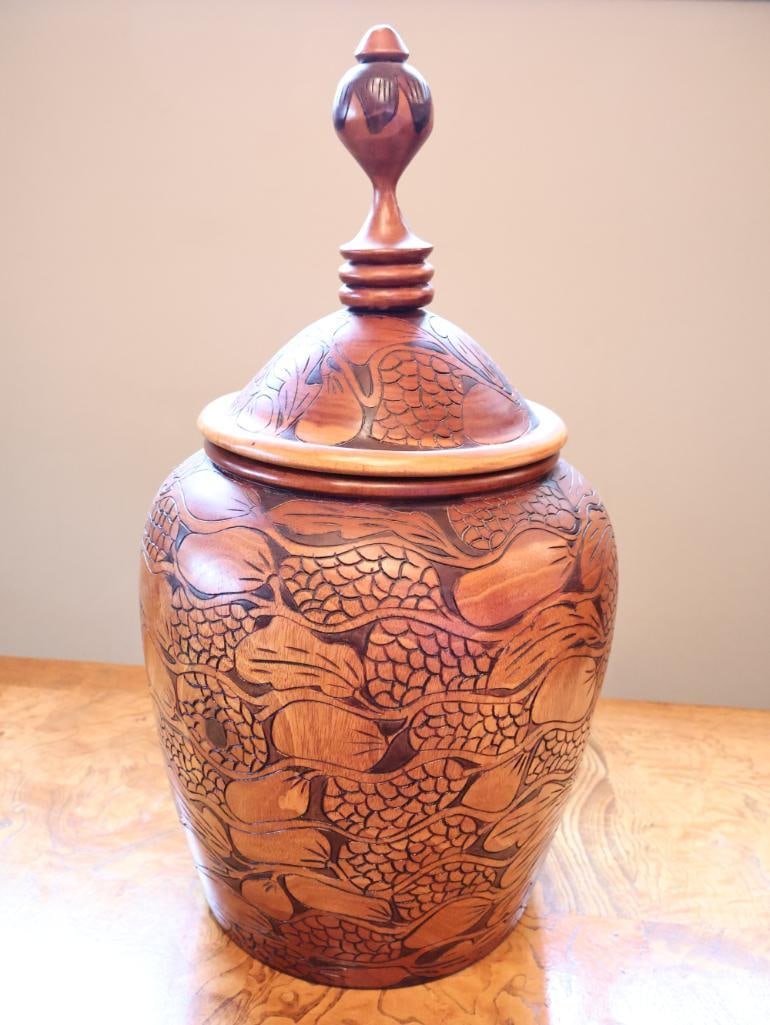 Large Hand-Carved Wood Covered Urn with Floral & Foliate Motif, 19": Large decorative hand-carved wooden covered urn featuring an elongated cylindrical body with deeply incised floral, leaf, and textured motifs throughout. Finished in contrasting warm honey and dark br