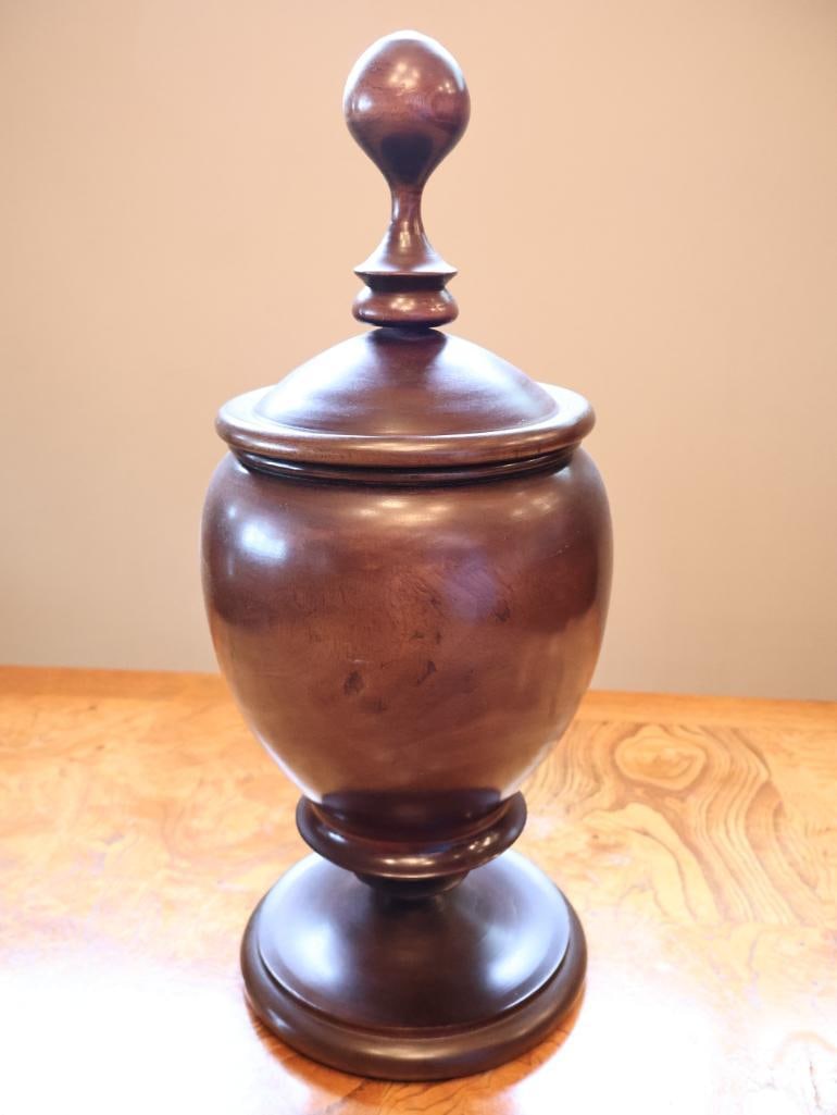 Large Turned Wood Pedestal Urn with Lid & Finial Approx. 19": Large decorative turned wood pedestal urn featuring a rich dark brown finish, rounded body, raised footed base, fitted lid, and substantial turned finial. The interior shows a warm natural/reddish woo