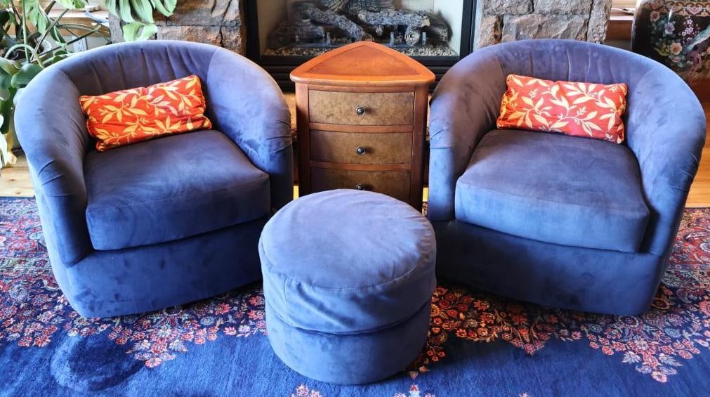 Pair of Blue Swivel Chairs, Rolling Ottoman & End Table: Coordinating four-piece seating group featuring two plush blue upholstered swivel barrel chairs, a matching round ottoman with casters, and a triangular wood three-drawer end table. Chairs include