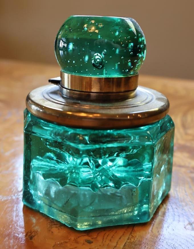 Vintage Emerald Green Glass Hinged Inkwell with Metal Mount: Vintage emerald/teal green glass desk inkwell featuring a substantial faceted octagonal base, molded starburst underside. Please review photos for condition.