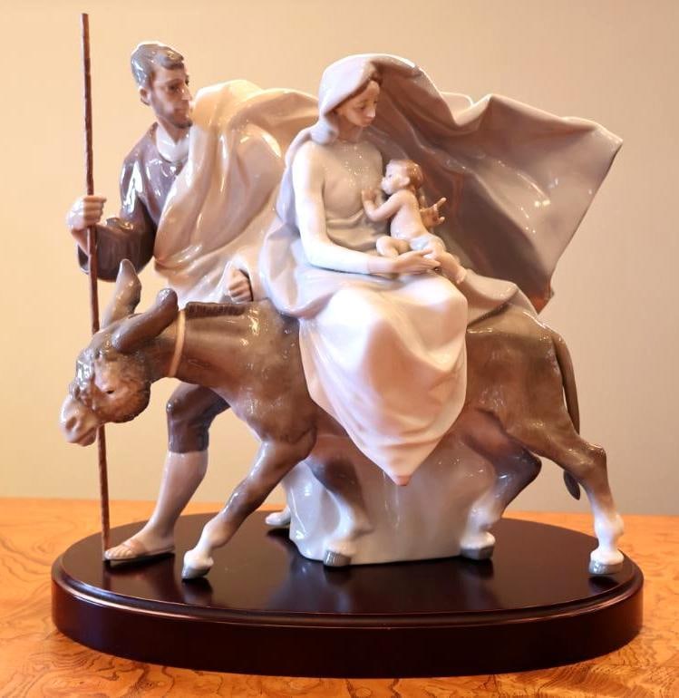 Large Lladro Holy Family Flight into Egypt Porcelain Figural Group on Wood Base: Lladro porcelain Holy Family figural group depicting the Flight into Egypt, with Mary holding the infant Jesus while riding a donkey accompanied by Joseph with staff. Porcelain group measures