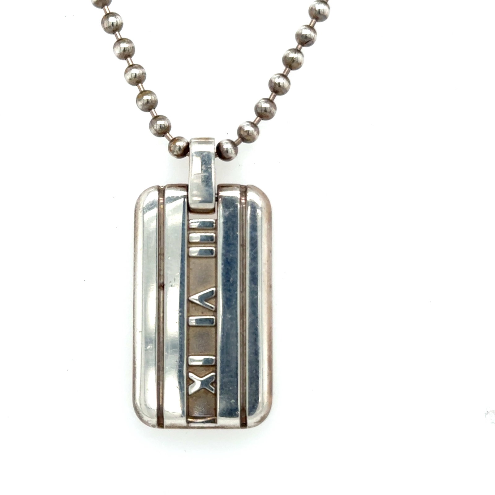 Tiffany & Co. Atlas Dog Tag Pendant on Beaded Chain, Roman Numerals 3-6-9,: Tiffany & Co. Atlas Dog Tag Pendant on Beaded Chain Description: A bold and recognizable design from Tiffany & Co., this Atlas collection dog tag pendant features the iconic Roman numeral moti