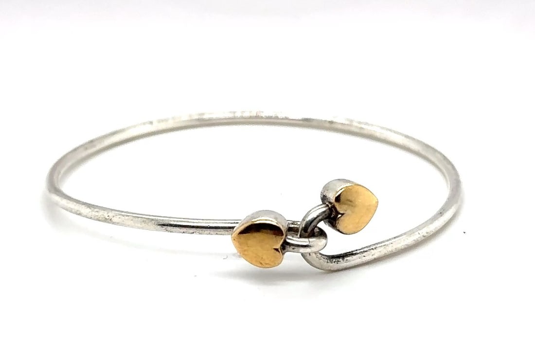 Tiffany & Co. Sterling Silver & 18k Gold Heart Cross-Over Bypass Bracelet, 8.5g, 1990: Tiffany & Co. Sterling Silver and 18k Gold Heart Cross-Over Bypass Bracelet Description: A charming and elegant bracelet from Tiffany & Co., featuring a heart-shaped cross-over bypass design in sterli