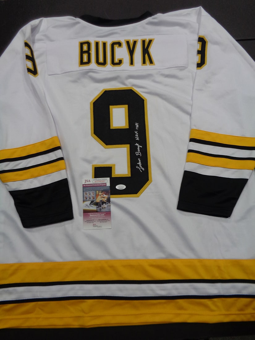 Johnny Bucyk Boston Bruins Autographed & Ins Custom Hockey Jersey JSA coa: Johnny Bucyk Boston Bruins Autographed & Inscribed "HOF 1981" Custom Hockey Jersey JSA Witnessed coa - Autograph Location & coa # may vary JERSEY SIZE EXTRA LARGE - CUSTOM JERSEY MEANS NO LOGOS, NO