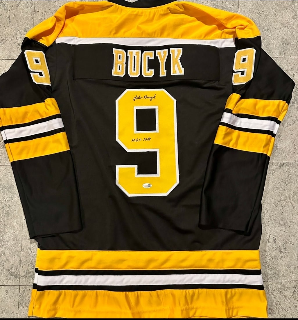 Johnny Bucyk Boston Bruins Autographed & Ins Custom Hockey Jersey JSA coa: Johnny Bucyk Boston Bruins Autographed & Inscribed "HOF 1981" Custom Hockey Jersey JSA Witnessed coa - Autograph Location & coa # may vary JERSEY SIZE EXTRA LARGE - CUSTOM JERSEY MEANS NO LOGOS, NO