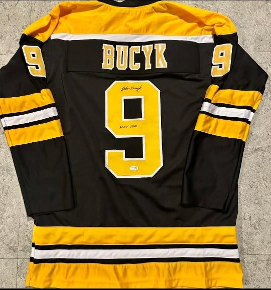 Johnny Bucyk Boston Bruins Autographed & Ins Custom Hockey Jersey JSA coa: Johnny Bucyk Boston Bruins Autographed & Inscribed "HOF 1981" Custom Hockey Jersey JSA Witnessed coa - Autograph Location & coa # may vary JERSEY SIZE EXTRA LARGE - CUSTOM JERSEY MEANS NO LOGOS, NO