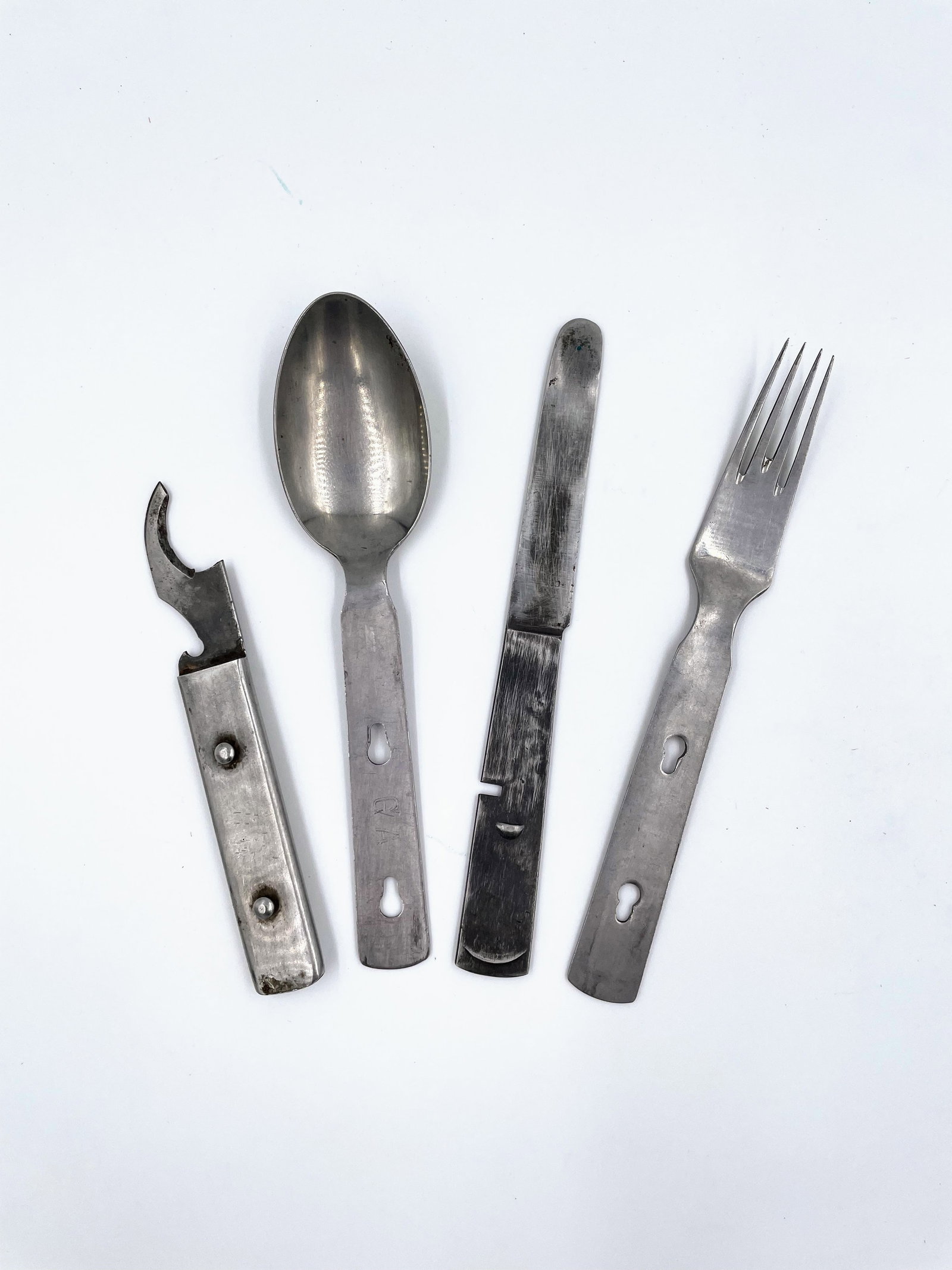 1940s German Military Cutlery Set: This lot consists of four pieces of WWII-era German military field cutlery, including a spoon, fork, knife, and combination can/bottle opener. Each piece is constructed from stainless steel or similar