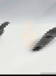 Human Effigy Pipe: Presented is a finely crafted human effigy pipe carved from stone, depicting a seated figure with detailed facial features and attire. The piece features a central bowl and hollow stem channel. This a