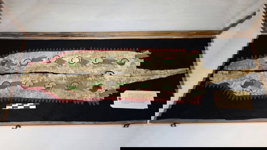 Dog Soldier Otter Sash - pre 1900: Otter pelt sash with mirror and ribbon accents set on a red-trimmed backing. Displayed in a fitted case, showing traditional design elements associated with warrior societies.reference: native america