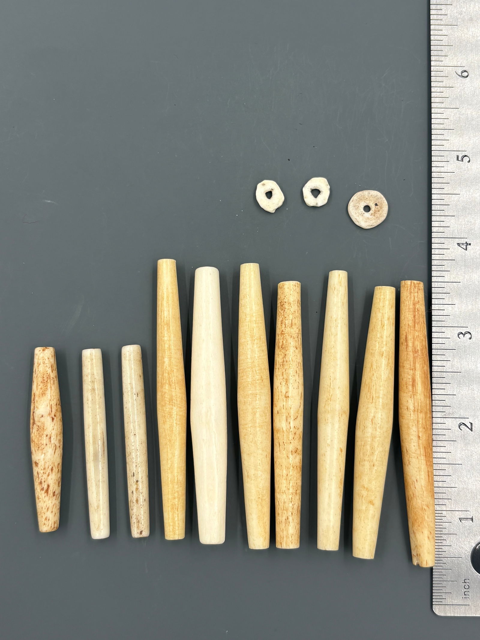 Bone Hairpipes: Group of carved bone hairpipes in various lengths, each with a tapered cylindrical form and smooth, polished surfaces. Used for chokers and breastplates. Keywords: native american, indian artifact, ar