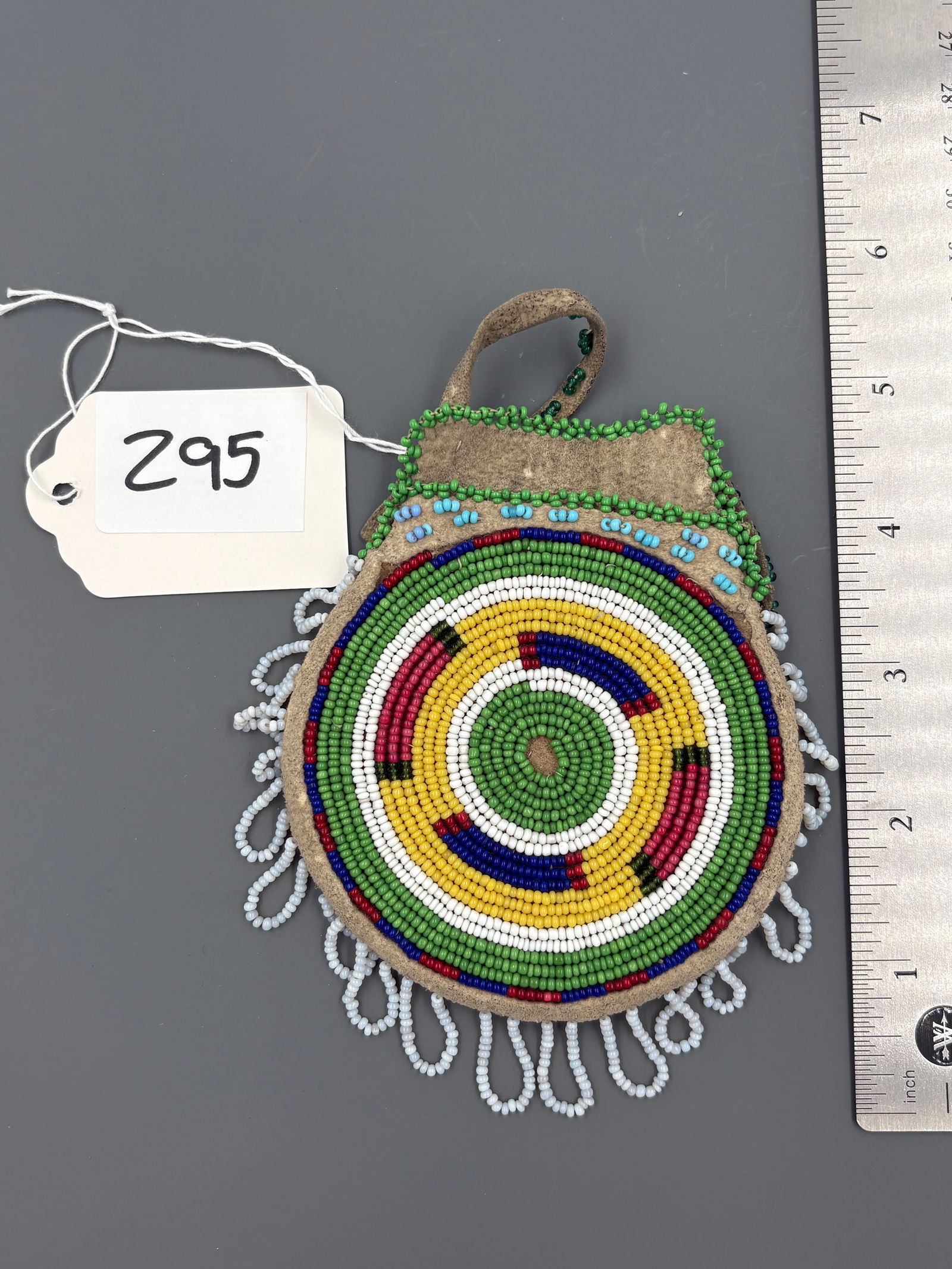 Beaded Medallion Pouch - Turn of the Century: Round leather pouch covered in multicolored beaded concentric rings with looped bead fringe around the lower edge and a simple leather suspension loop. Keywords: native american, indian artifact, arro