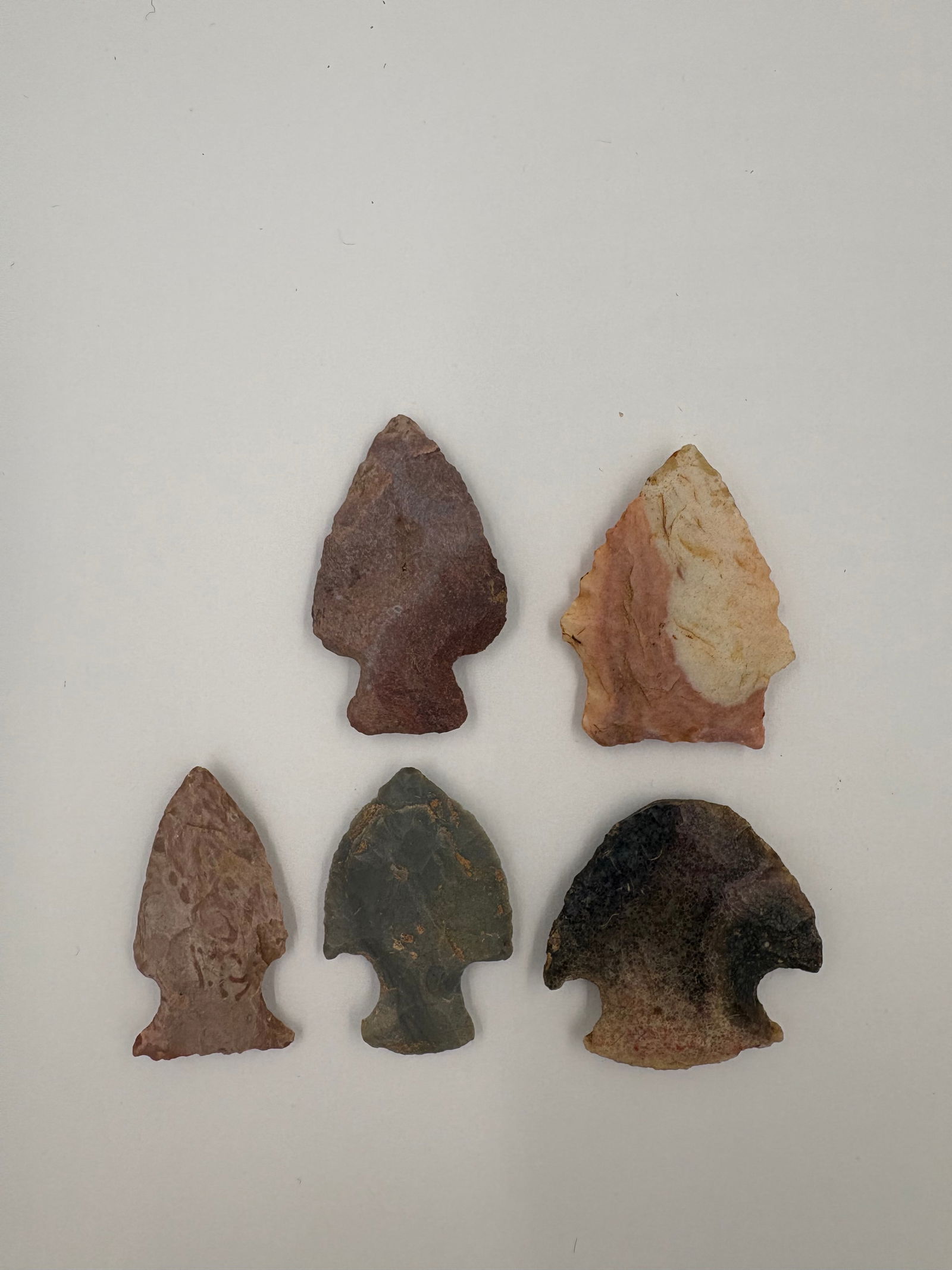 4 Colorful Hopewell Points: Four colorful Hopewell projectile points crafted from varying stone with triangular blades and stemmed or notched hafting bases. Colors range from red-brown and creamy tan to gray-green and dark