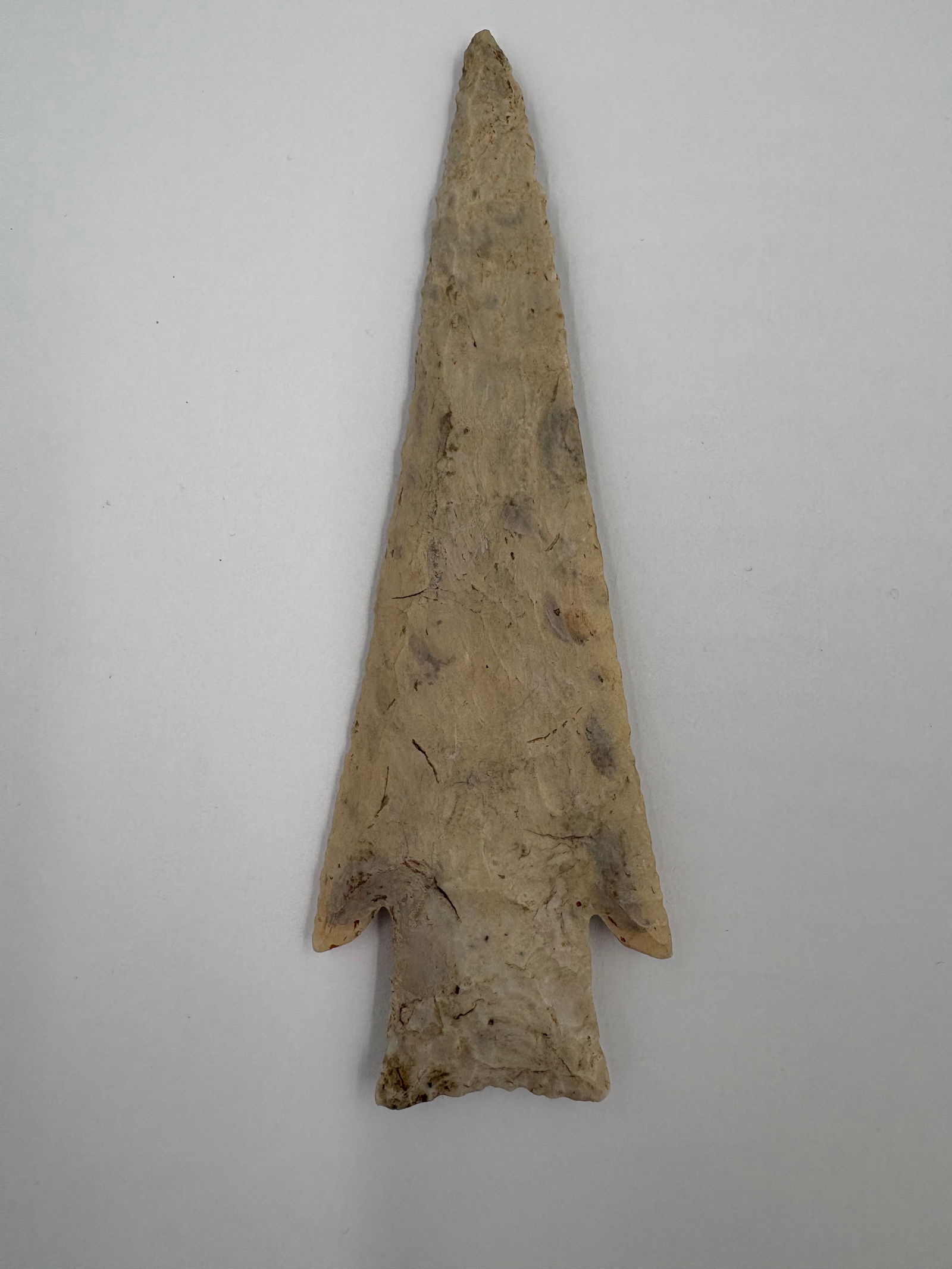 *Restored* Hardin: Restored Hardin-style stone projectile point with a long, narrow triangular blade, pronounced barbed shoulders, and a stemmed base. Bifacial flake work covers both faces and the piece displays a pale