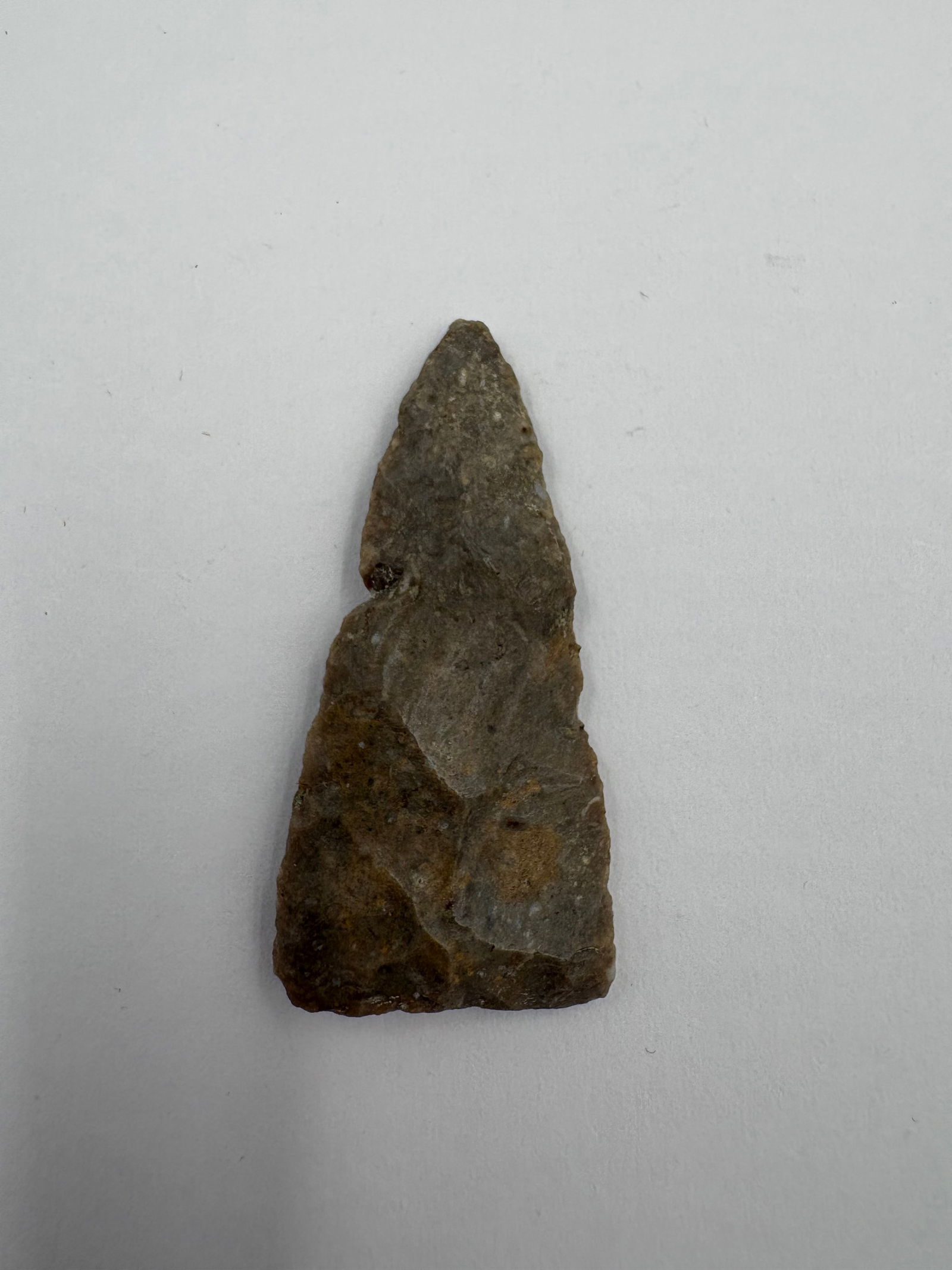 Plains Triangular Point, Motley COA: Triangular stone point fashioned from high-grade Florence chert, 1 3/4 inches long. Gray-brown coloration with tan mineral patches and numerous flake scars across the faces and edges. Acute tip with