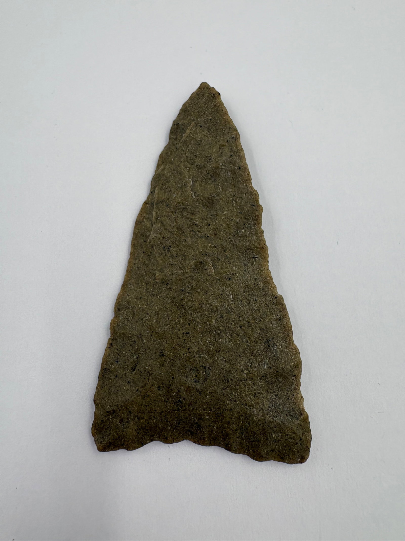 Plains Triangle, Motley COA: Plains-style triangular stone point made from silicified sandstone, measuring 2 11/16 inches in length. The piece has a green-gray sandy texture with fine bifacial flaking across both faces. Narrow, a