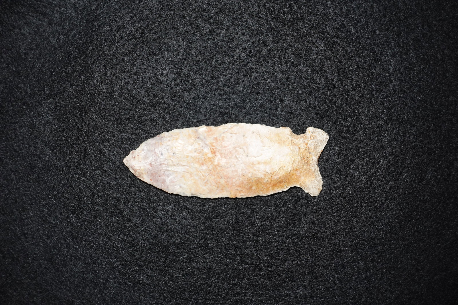 Osceola: Elongated lanceolate flaked stone point with fine bifacial flaking and a narrow, tapered tip. Pronounced stemmed base terminates in a small basal ear and edges show evident pressure-flake retouch.