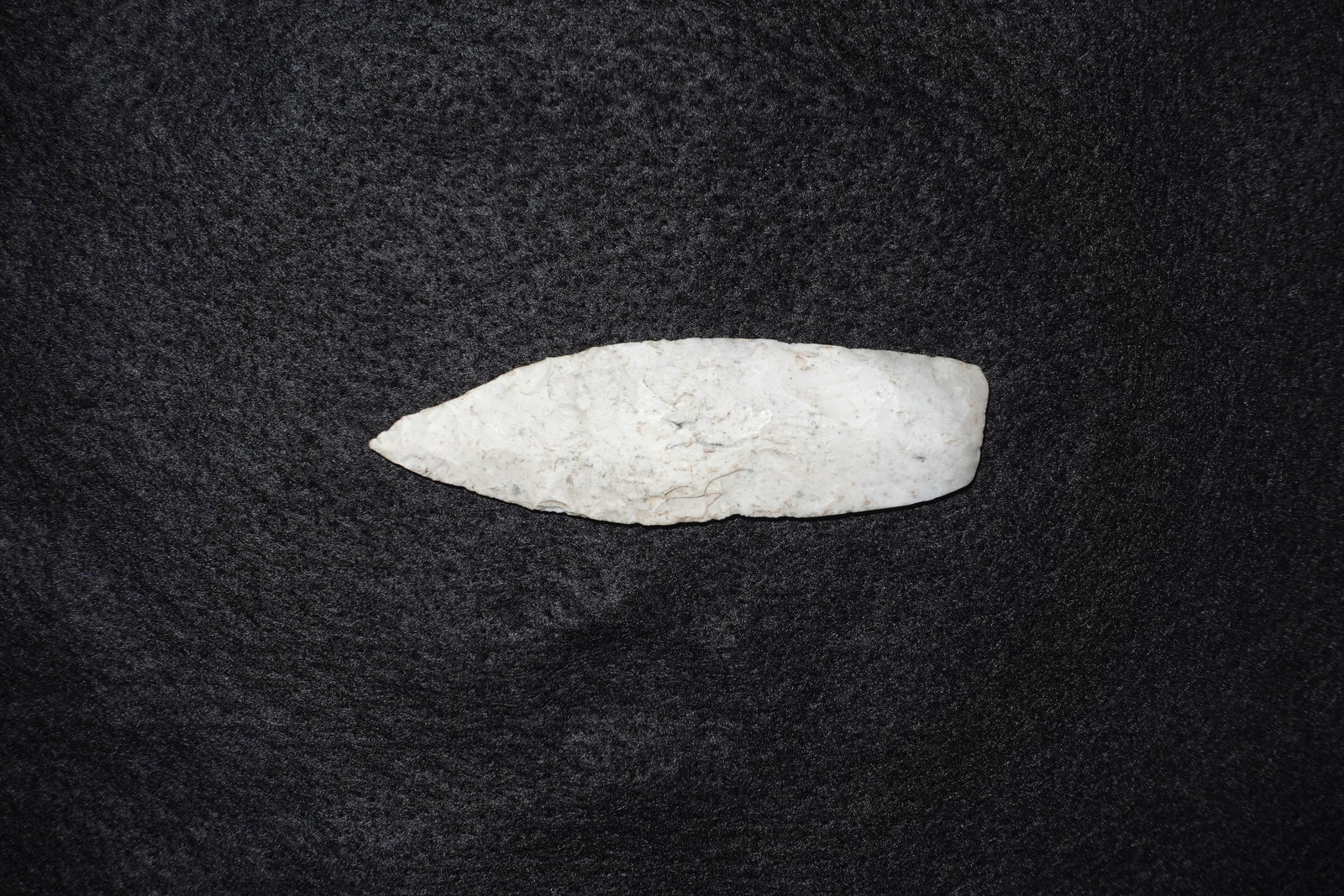 Agate Basin: Elongated bifacial white stone point with a tapered tip and a broader rounded base. Both faces display fine flake scars and visible edge retouch with creamy white coloration and faint brown mineral st