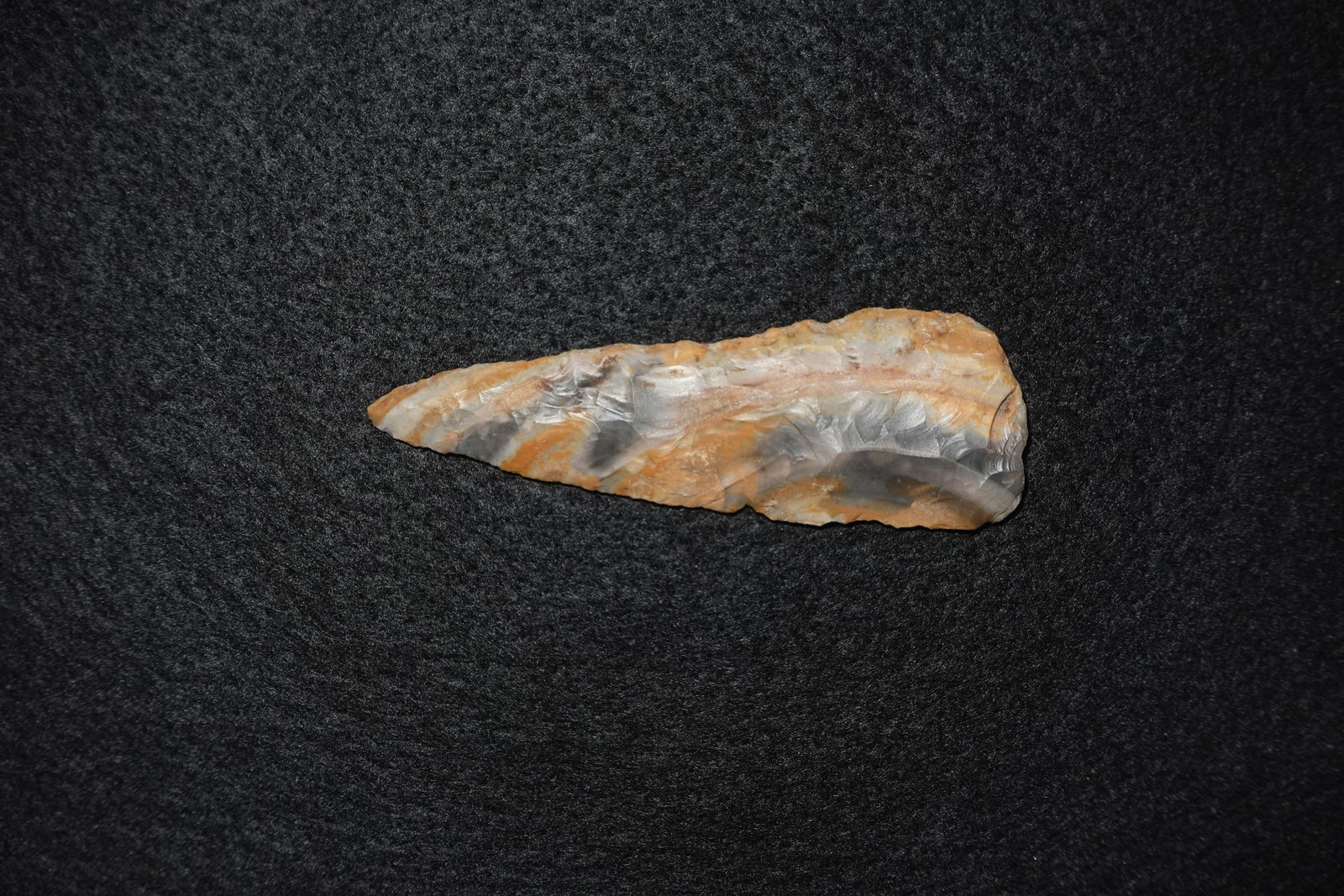 Cobbs: Elongated bifacial flaked chert blade with a narrow, tapered tip and broader basal end. Rippling flake scars cover both faces with fine pressure-retouch along the edges and a mix of gray and