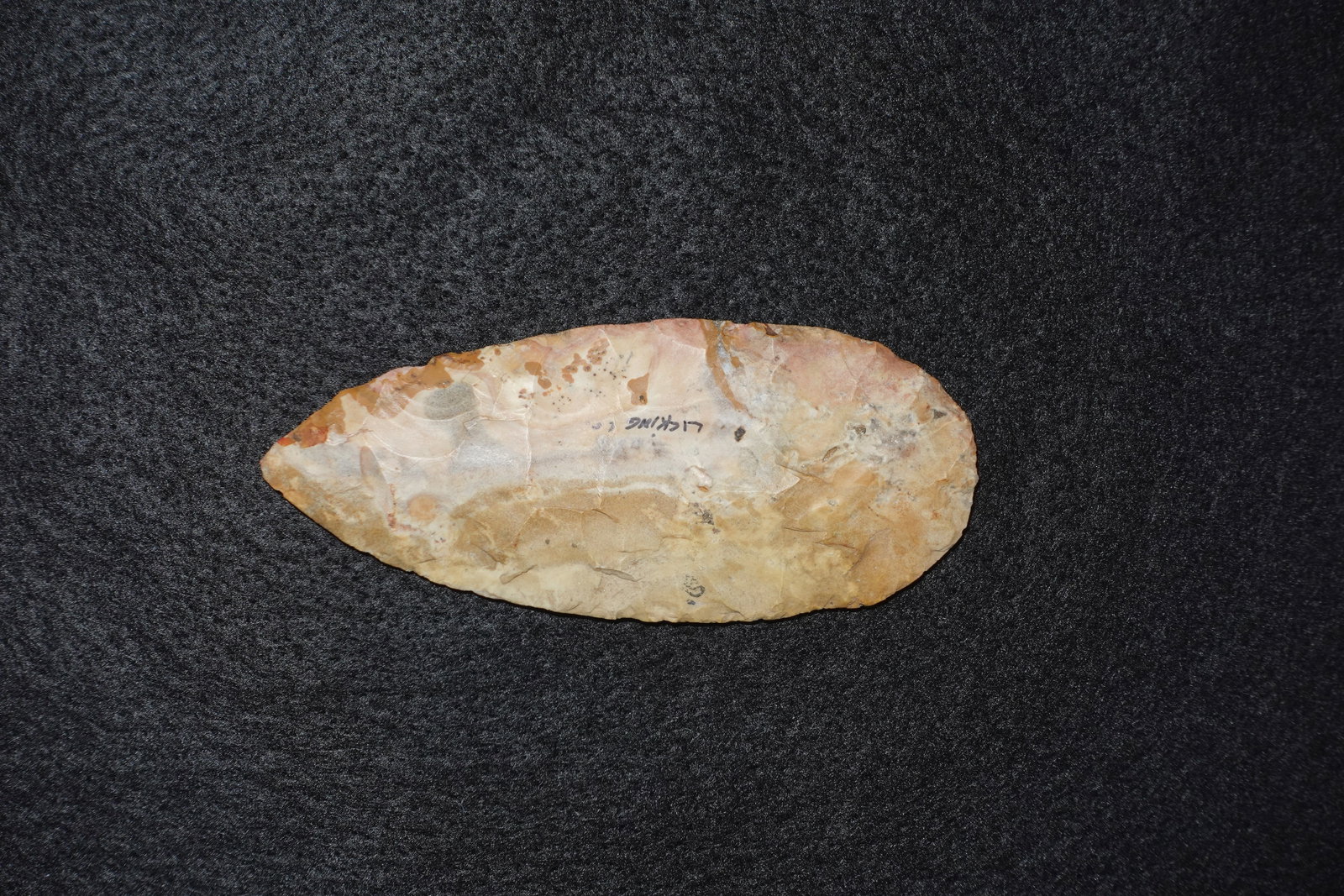 Cache Blade #3: Flaked chert blade with an elongated ovate profile and bifacially worked surfaces showing distinct percussion and pressure flake scars. Surface tones range from cream to tan with pink-brown staining