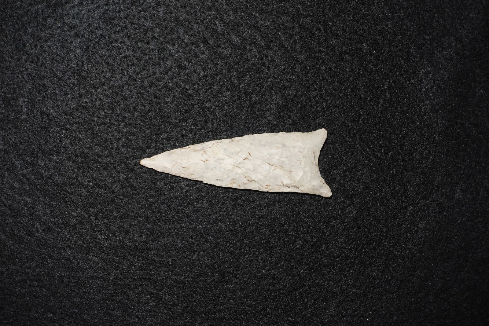 Dalton: A long, triangular flaked stone projectile point crafted from light cream to off-white chert. Bifacial flaking creates pronounced flake scars across both faces with a tapered tip and a narrow,