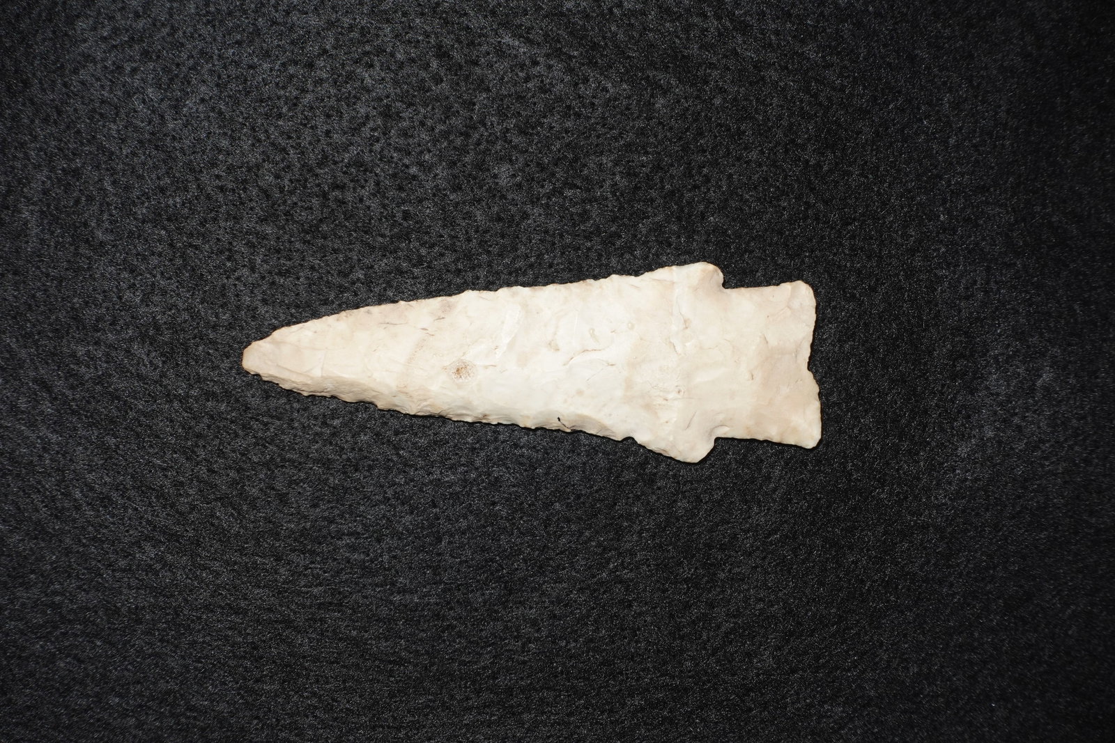 Hardin: Hardin-style elongated projectile point crafted from a light cream to buff stone. Blade tapers to a narrow tip with visible bilateral flaking and a distinct notched base consistent with hafting. Surfa