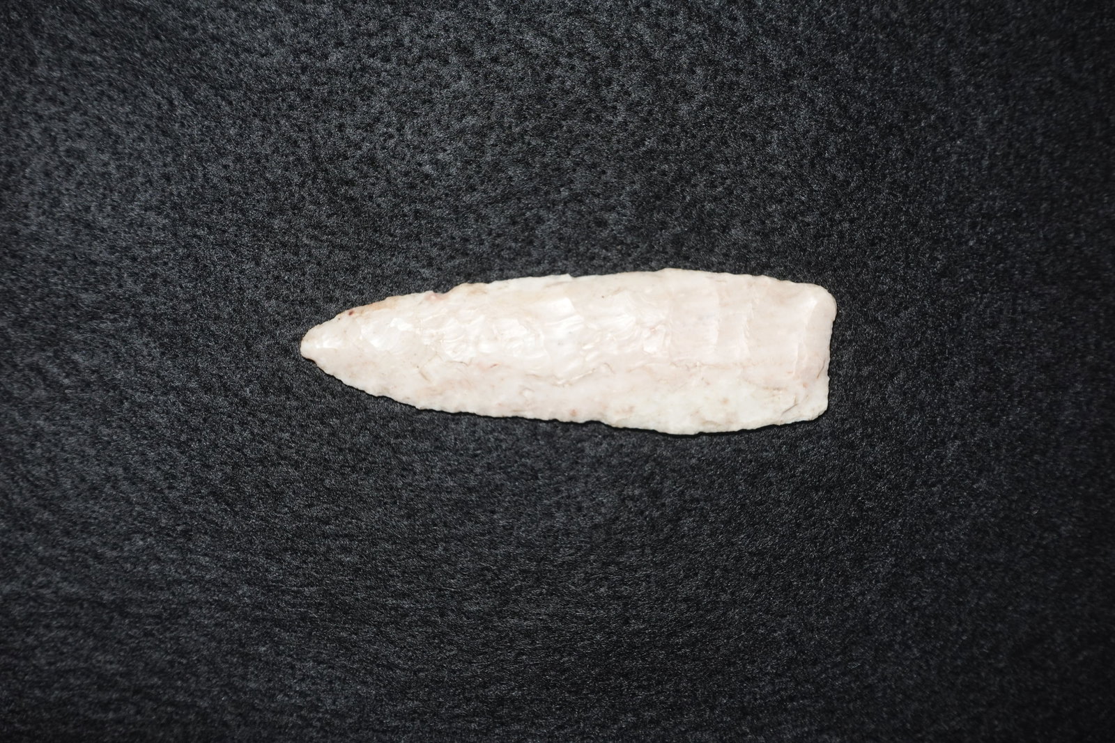 Agate basin: Elongated lanceolate agate blade with bifacial flaking that tapers to a pointed tip and a straighter, slightly squared base. Milky white to pale pink translucent stone exhibiting flake scars across