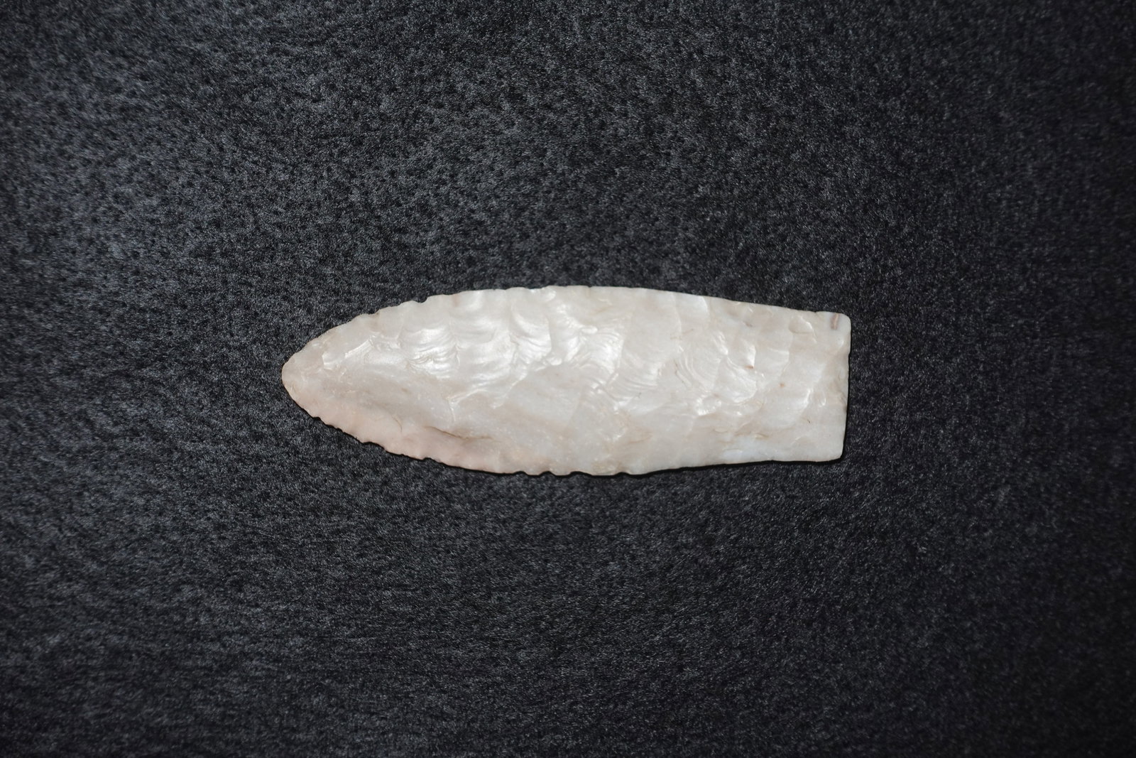 Midland: Hand-flaked white translucent stone lanceolate blade with a tapered point and straight basal edge. Both faces exhibit overlapping flake scars from bifacial knapping and fine pressure-flaked edge remov