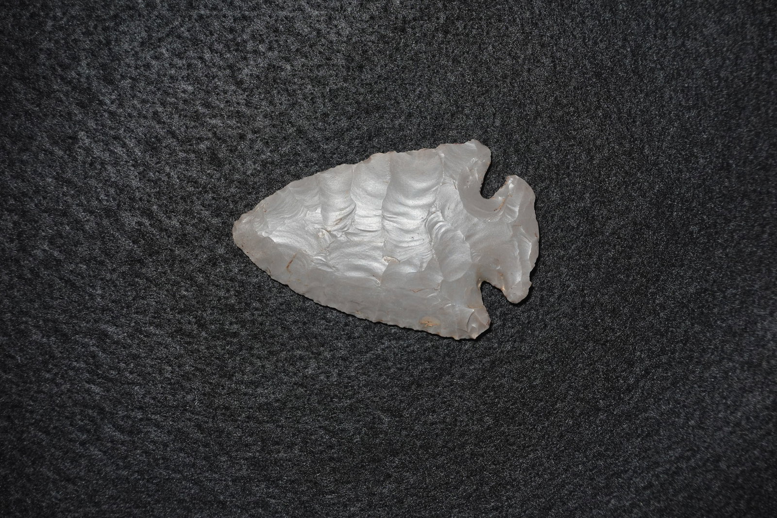 Dovetail: Hand-flaked translucent gray chert projectile point with a broad triangular blade and a distinct notched stem forming a dovetail-style base. Bifacial flaking displays pronounced ripple-like flake