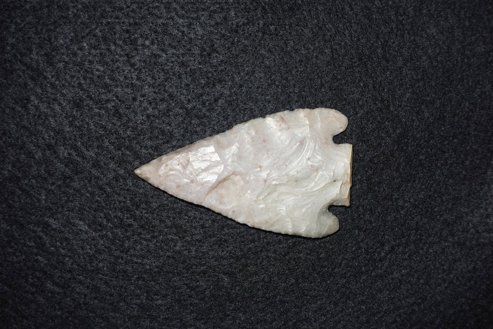 San Saba: Translucent white-to-cream flaked stone projectile point with pronounced bifacial flaking and overlapping pressure-flake scars creating a scalloped surface. Triangular blade tapers to a fine tip and f
