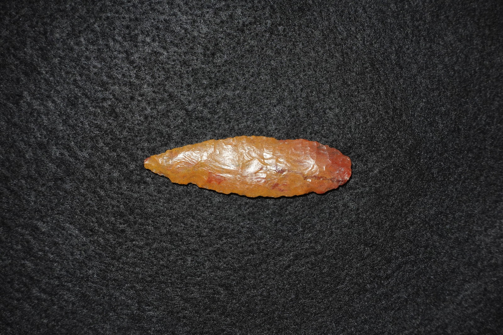 Northern Plains Agate Blade: Elongated agate blade featuring bifacial flaking and a sharply tapered form. Polished orange-to-red agate displays glossy surfaces with flake scars and fine edge retouch. Edge shows regular