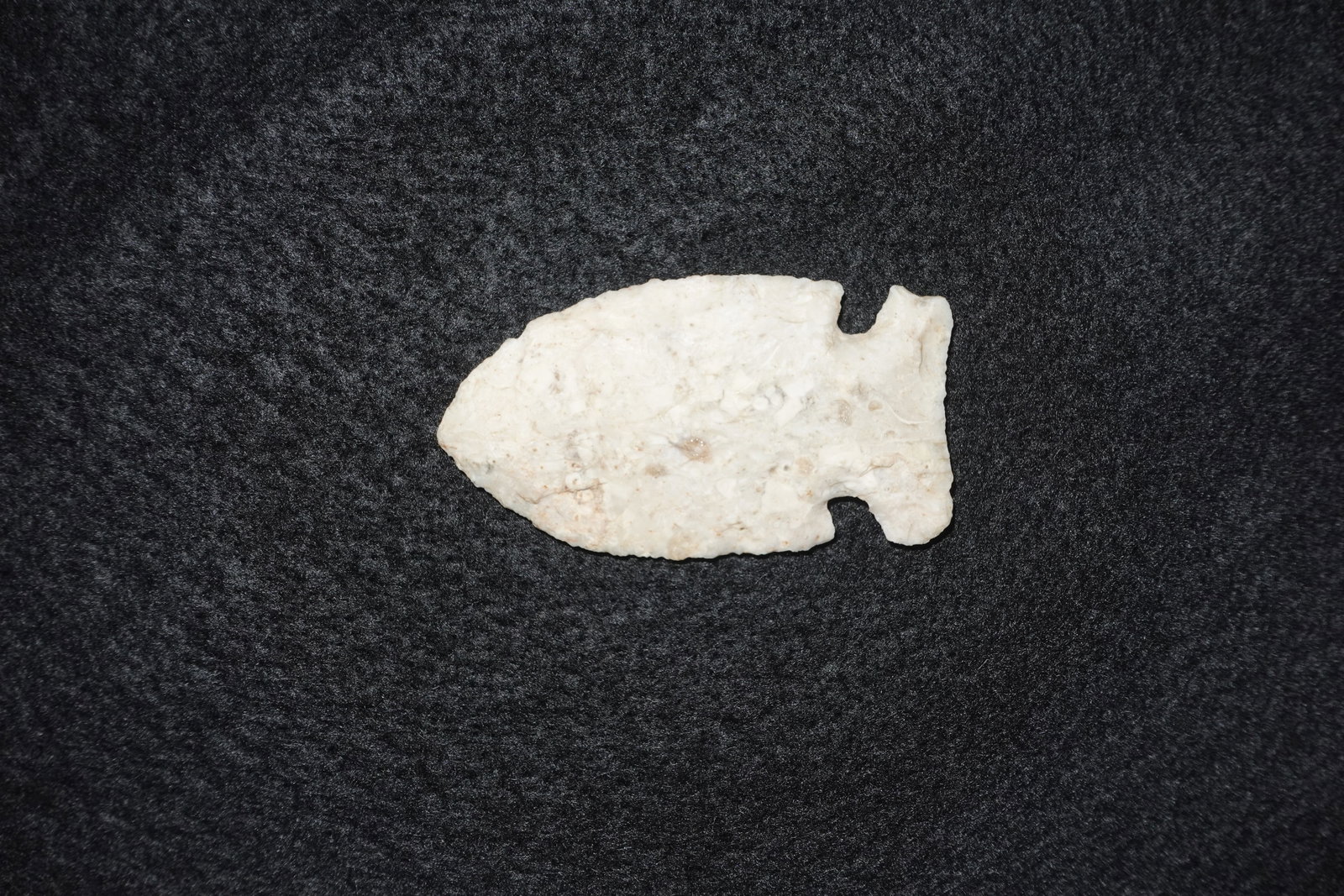 Hemphill: Creamy white flaked stone projectile point with a broad leaf-shaped blade and pronounced basal notches that form a short stem. Surfaces display percussion and pressure flake scars across both faces