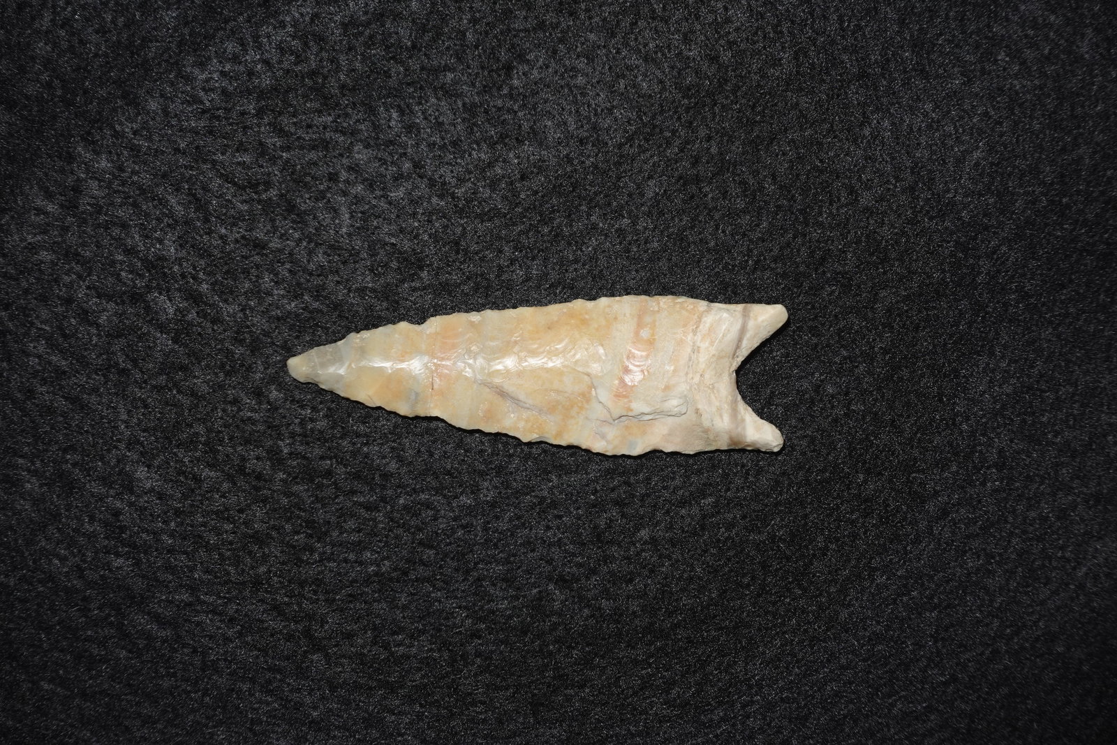 Beautiful Mozarkite Dalton: Mozarkite Dalton projectile point with cream, tan and pale pink banding and a subtle translucent sheen. Narrow lanceolate blade exhibits pronounced flake scars and fine pressure-flaked edges terminati