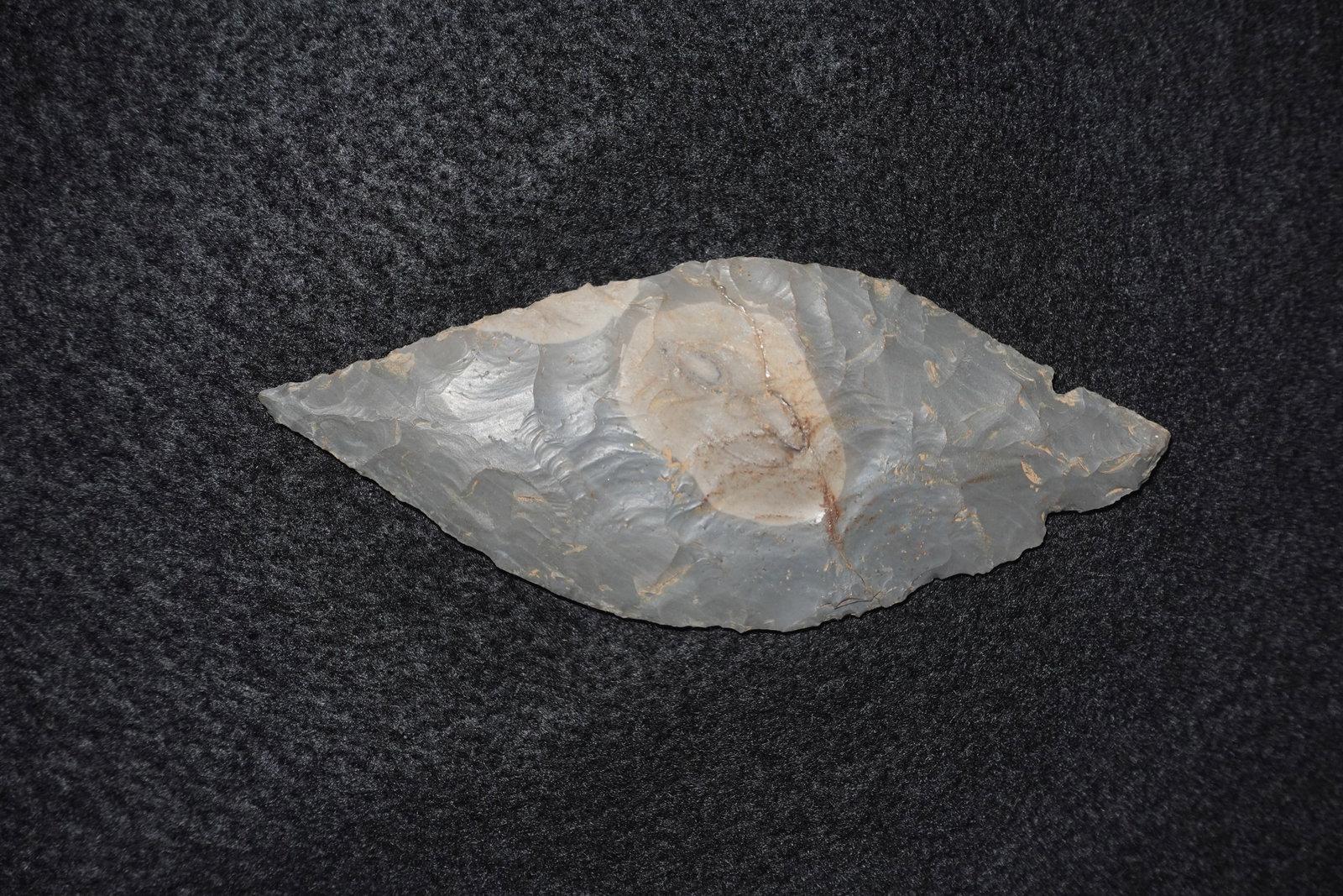 Turkeytail: Bifacially flaked gray chert blade with pronounced conchoidal flake scars and a central lighter-toned cortex patch. One edge has a repaired break with adhesive along a fracture line. Found by Randy Wi
